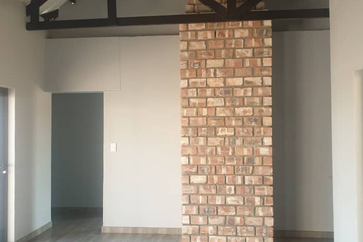 Spacious living area featuring high vaulted ceilings with exposed timber trusses and a prominent floor-to-ceiling face brick fireplace chimney.