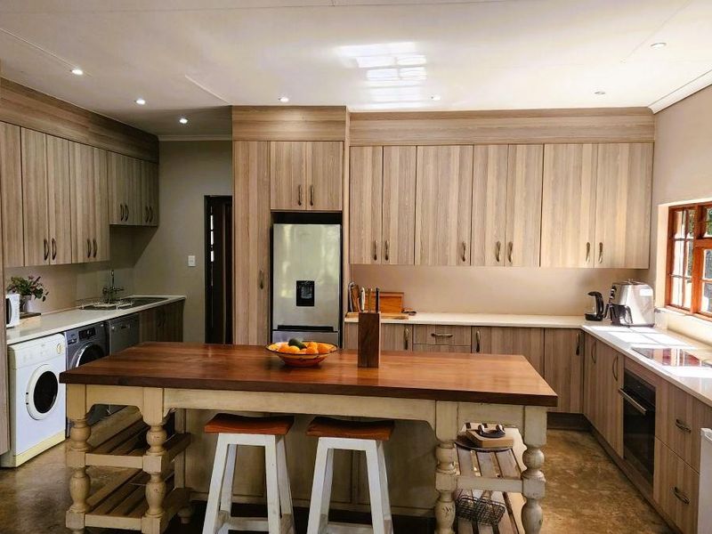 A well-appointed kitchen featuring extensive wood-finish cabinetry, integrated appliances, a central wooden island, and ample natural light from large windows.