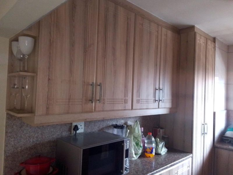 A kitchen area featuring wood-look laminate cabinetry, granite countertops, and built-in microwave space, offering functional storage and preparation surfaces.