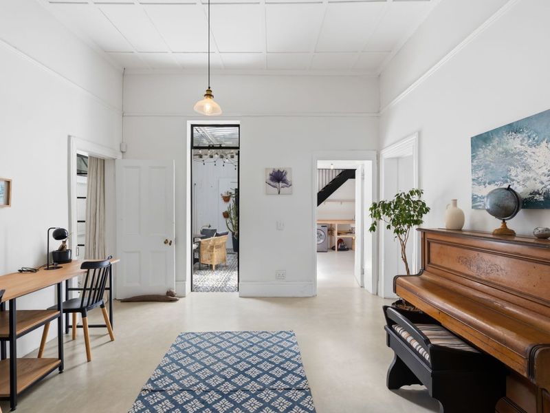 A bright and spacious living area featuring high coffered ceilings, neutral flooring, and multiple doorways leading to adjacent rooms.