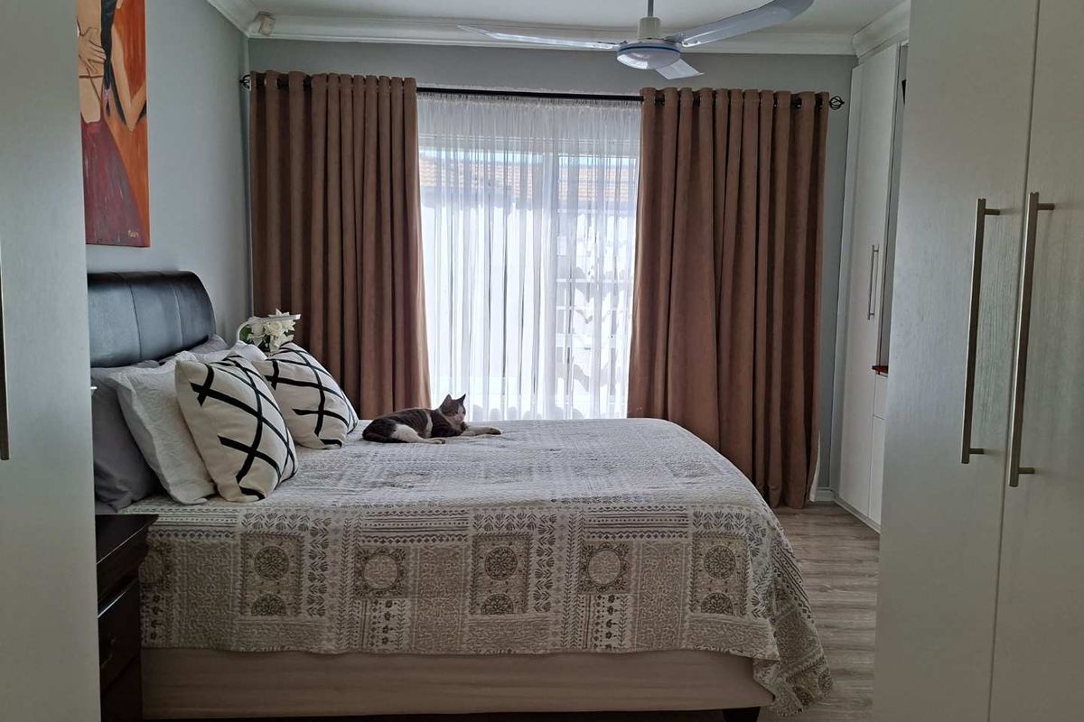 A well-maintained bedroom featuring built-in cupboards, laminate flooring, and a ceiling fan, offering a comfortable and functional living space.