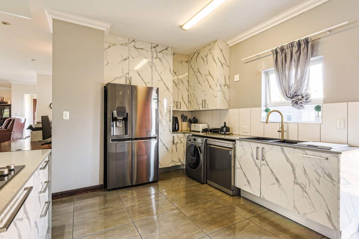 Modern kitchen featuring marble-effect cabinetry, brass faucet, undermount sink, and tiled flooring, offering a clean and contemporary aesthetic.