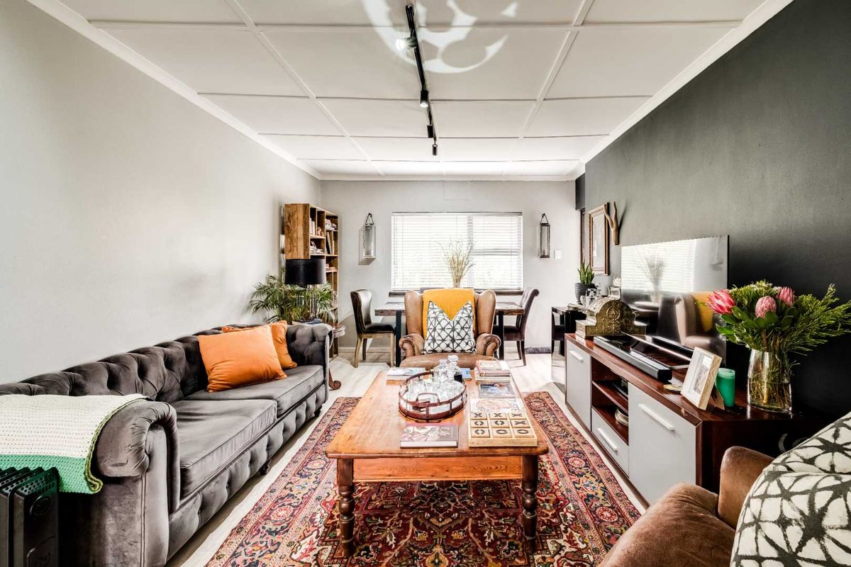 A cozy living room featuring a dark accent wall, track lighting, and a tiled ceiling, creating a warm and inviting atmosphere.
