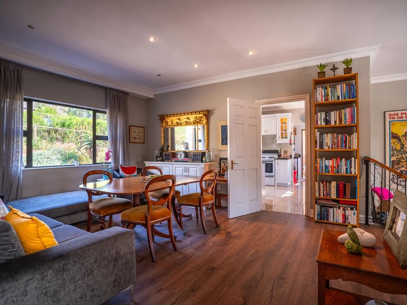 An open-plan living and dining area featuring laminate flooring, recessed downlighting, and a built-in window seat, with a view through to the kitchen.