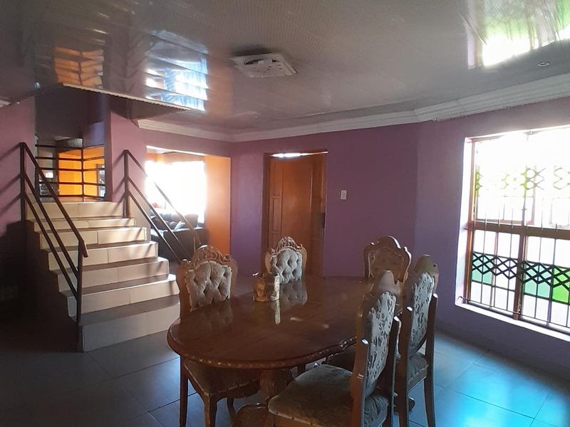 Dining area featuring tiled floors, a staircase with metal balustrades, and large windows with security bars.