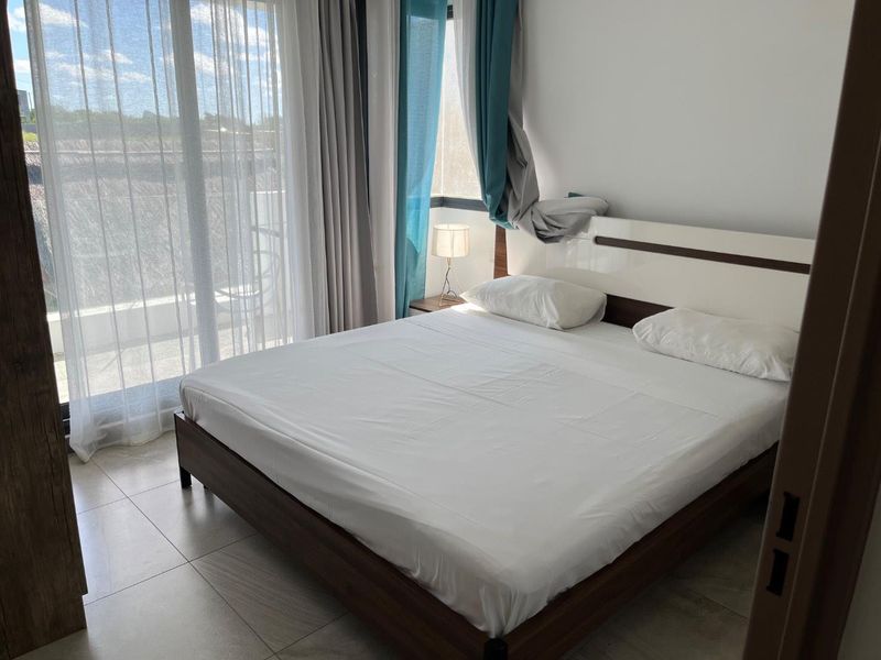 A bright bedroom featuring tiled flooring and a large sliding glass door providing access to an outdoor area.