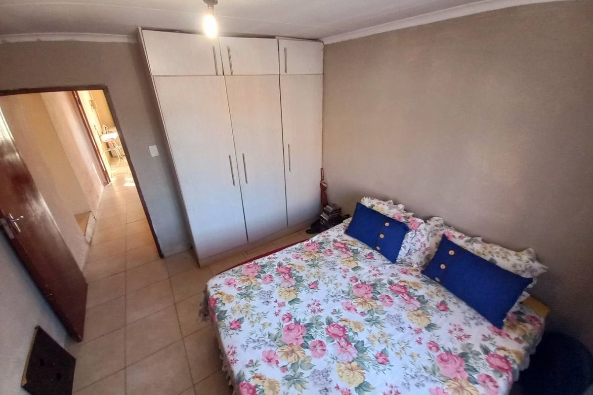 A functional bedroom featuring built-in floor-to-ceiling wardrobes and tiled flooring, providing practical storage and a neutral foundation for personal styling.