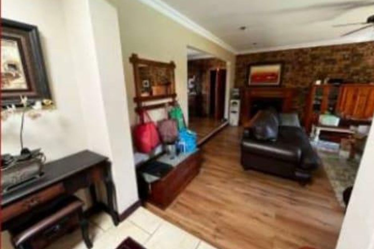 A living room featuring laminate flooring, a brick accent wall, and a fireplace, providing a warm and functional space for relaxation.