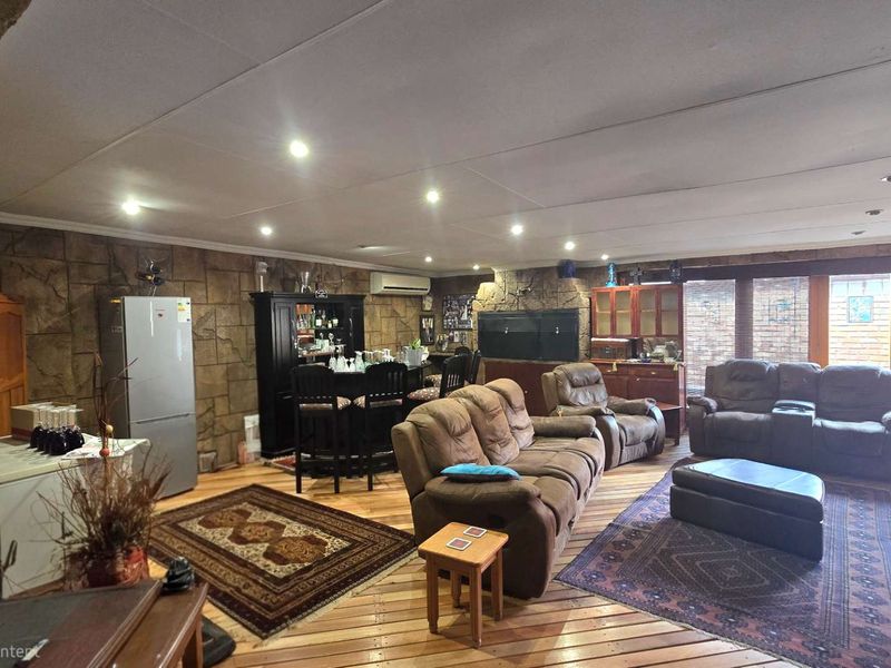 Spacious living area featuring a stone-clad feature wall, built-in fireplace, timber flooring, and recessed downlights, with direct access to the outdoor area.
