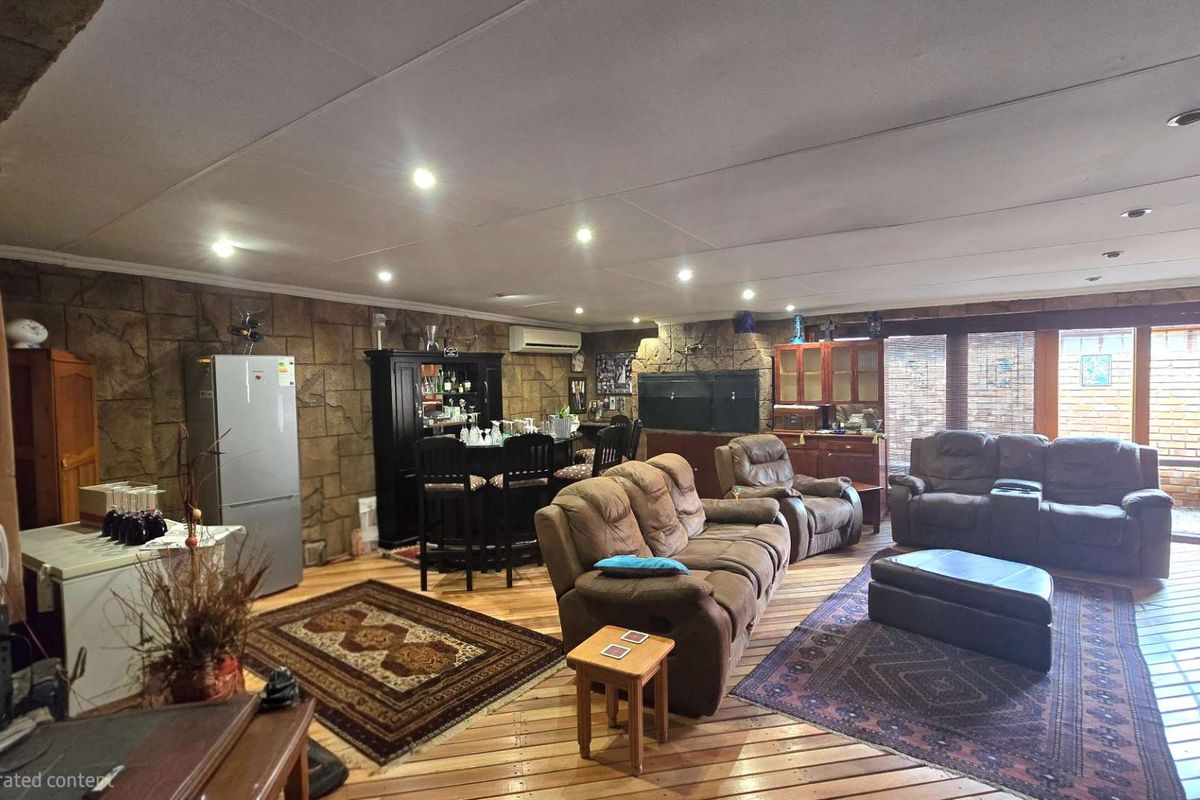 Spacious living area featuring a stone-clad feature wall, built-in fireplace, timber flooring, and recessed downlights, with direct access to the outdoor area.