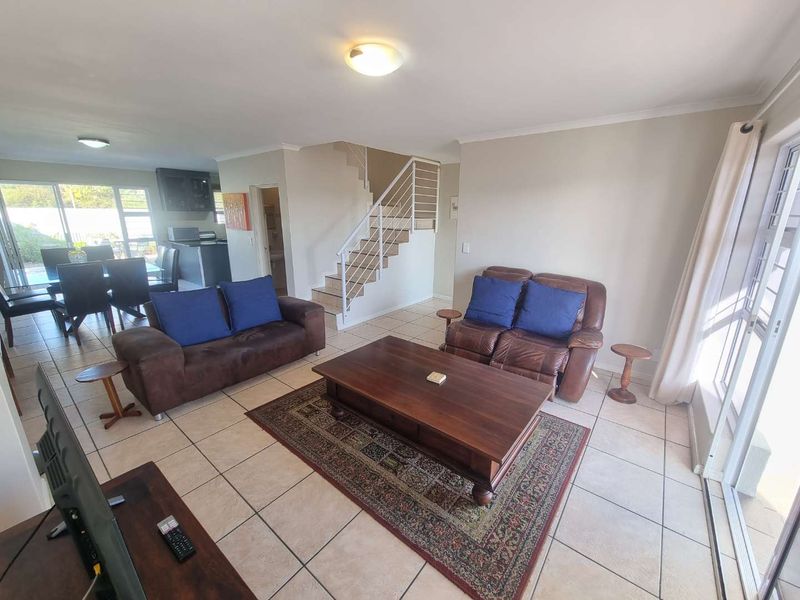 Open plan living and dining area featuring tiled floors, a staircase with metal balustrades, and sliding glass doors leading to the exterior.