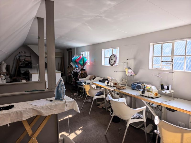 A functional office or studio space featuring a sloped ceiling, partition wall, and multiple windows providing natural light.