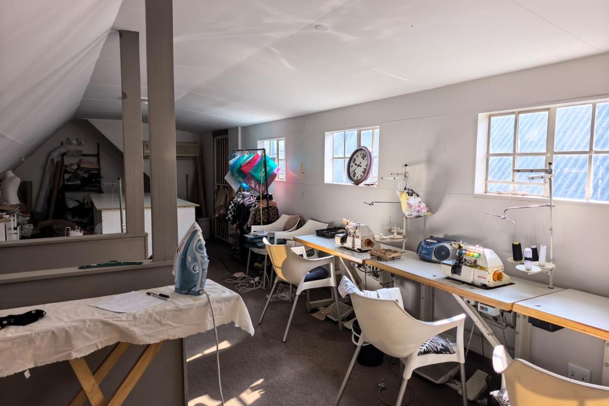 A functional office or studio space featuring a sloped ceiling, partition wall, and multiple windows providing natural light.
