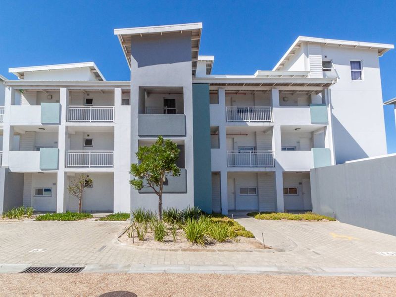 Front elevation of a modern multi-story apartment complex featuring paved parking, landscaped garden beds, and private balconies for each unit.