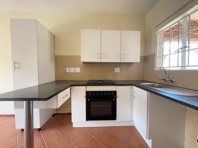 A functional kitchen featuring built-in cabinetry, a black hob and oven, laminate countertops, and a stainless steel sink with tiled backsplash.