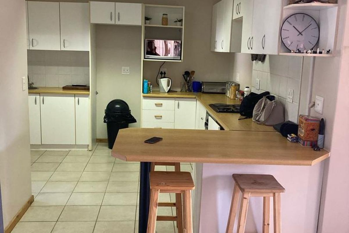 Functional kitchen featuring white cabinetry, laminate countertops, a breakfast bar, and tiled flooring, providing a practical layout for daily meal preparation.