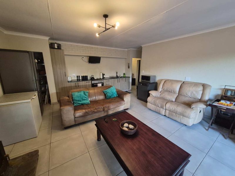 An open-plan living area featuring tiled floors and a compact kitchen with built-in cabinetry and integrated oven.