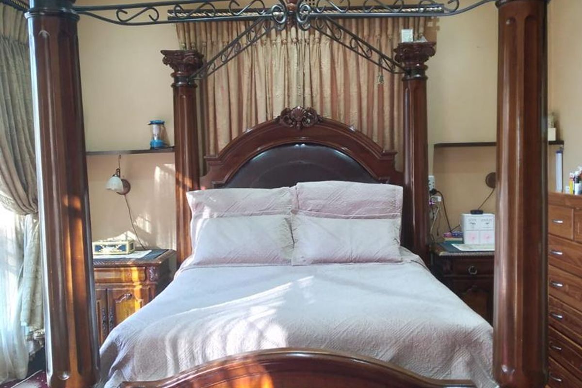 A spacious bedroom featuring recessed ceiling lighting and wall-mounted bedside shelving.