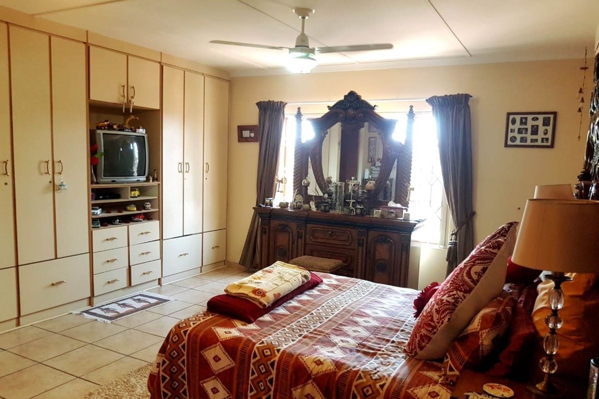Spacious bedroom featuring extensive built-in cabinetry with integrated shelving and a ceiling fan, offering ample storage and comfortable living space.