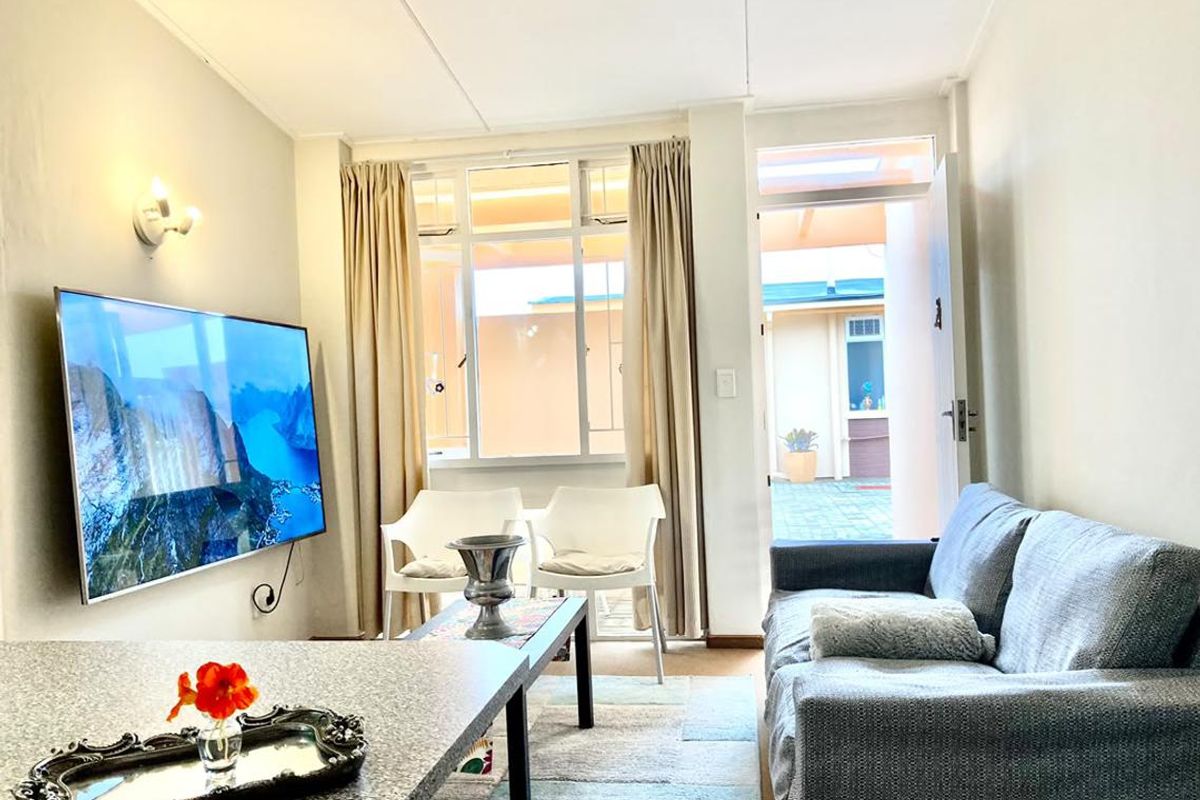 A bright and comfortable living room featuring a large window and direct access to an outdoor patio area.