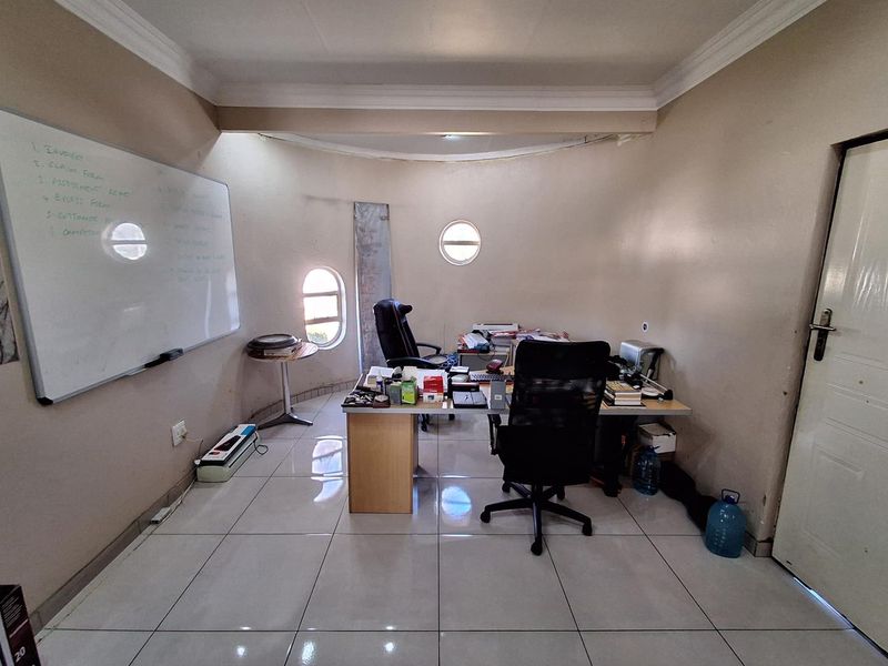 A functional office space featuring tiled flooring, coved ceilings, and unique porthole-style windows, providing a bright and practical workspace.