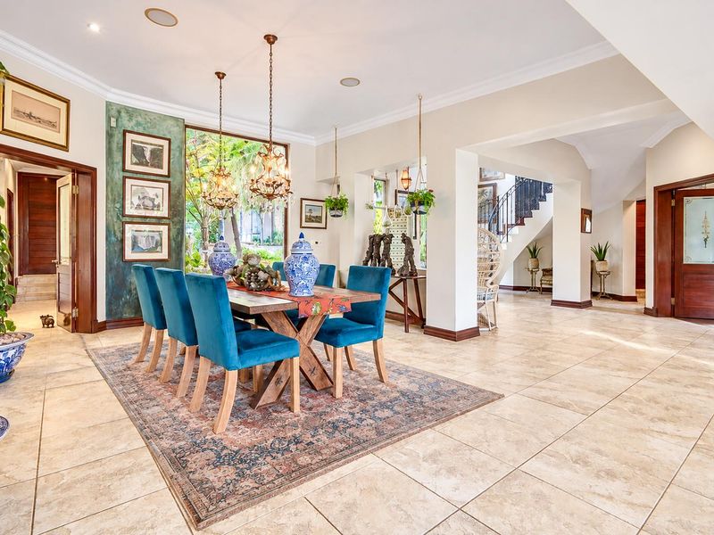 Spacious dining area featuring tiled flooring, recessed lighting, and an open-plan layout leading to a staircase with a decorative wrought iron railing.