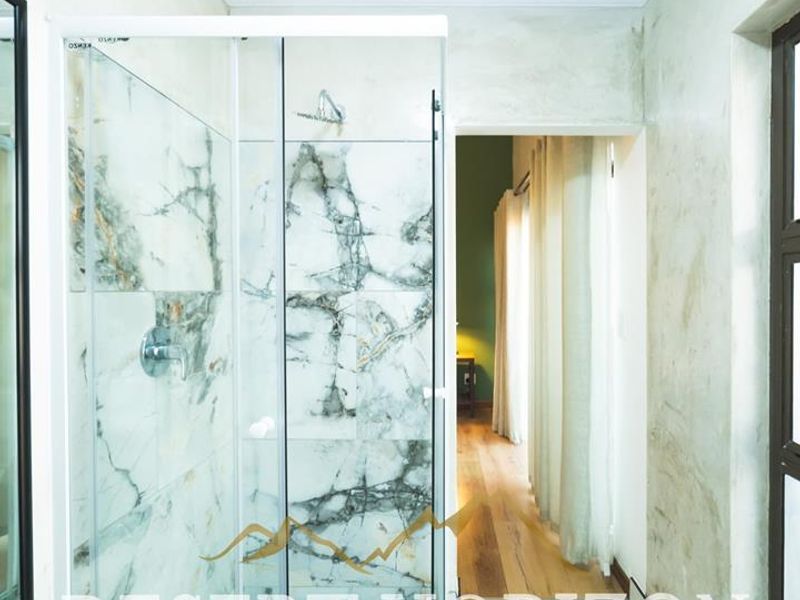 Modern bathroom featuring a glass-enclosed shower with marble-effect tiling and elegant ceiling cornice detailing.
