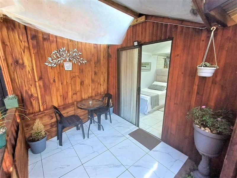 A covered patio area featuring timber wall cladding and tiled flooring, providing direct access to the interior bedroom space.