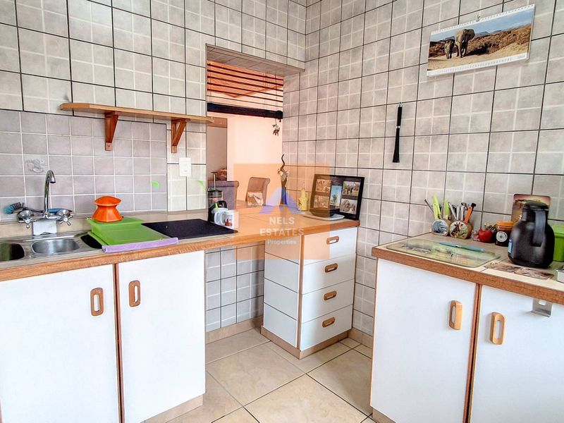 A functional kitchen featuring tiled walls, laminate countertops, and built-in cabinetry, offering a dated aesthetic ready for modernization.