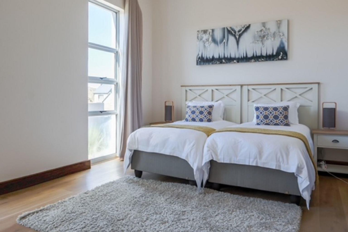 A bright and well-maintained bedroom featuring light timber flooring and a large window allowing for ample natural light.