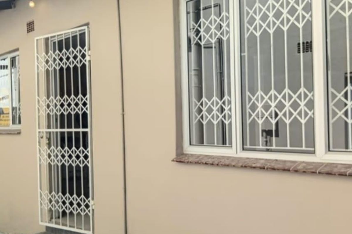 Rear exterior view of the property featuring security gates and window bars installed on the building facade.