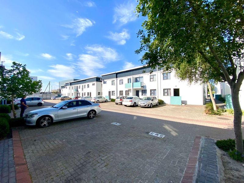 Exterior view of a multi-story apartment complex featuring a paved parking area and building facade.