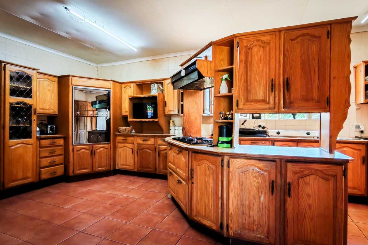 Spacious kitchen featuring extensive solid wood cabinetry, built-in oven, extractor fan, and tiled flooring, offering a traditional layout with ample storage space.