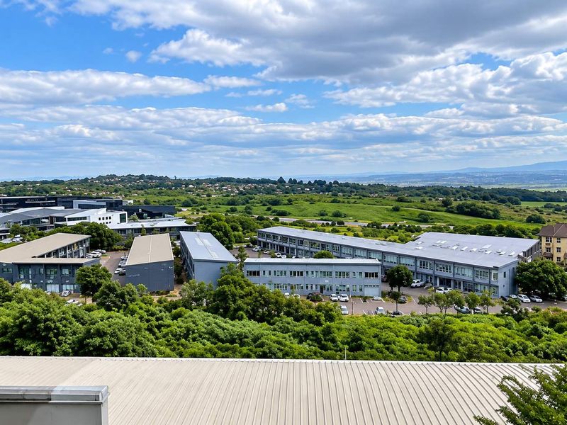 An elevated aerial view of a modern office park complex surrounded by lush greenery and scenic landscape.