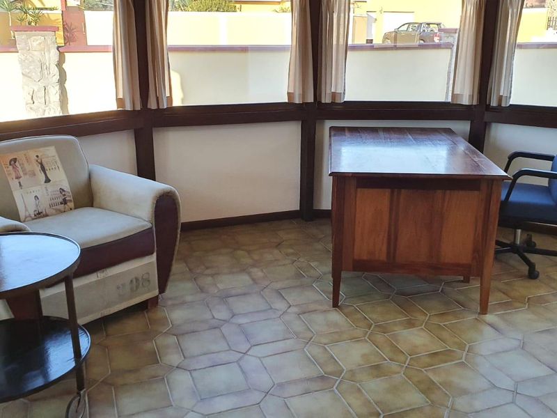 A sunlit home office featuring large windows and tiled flooring, providing a bright and functional workspace.
