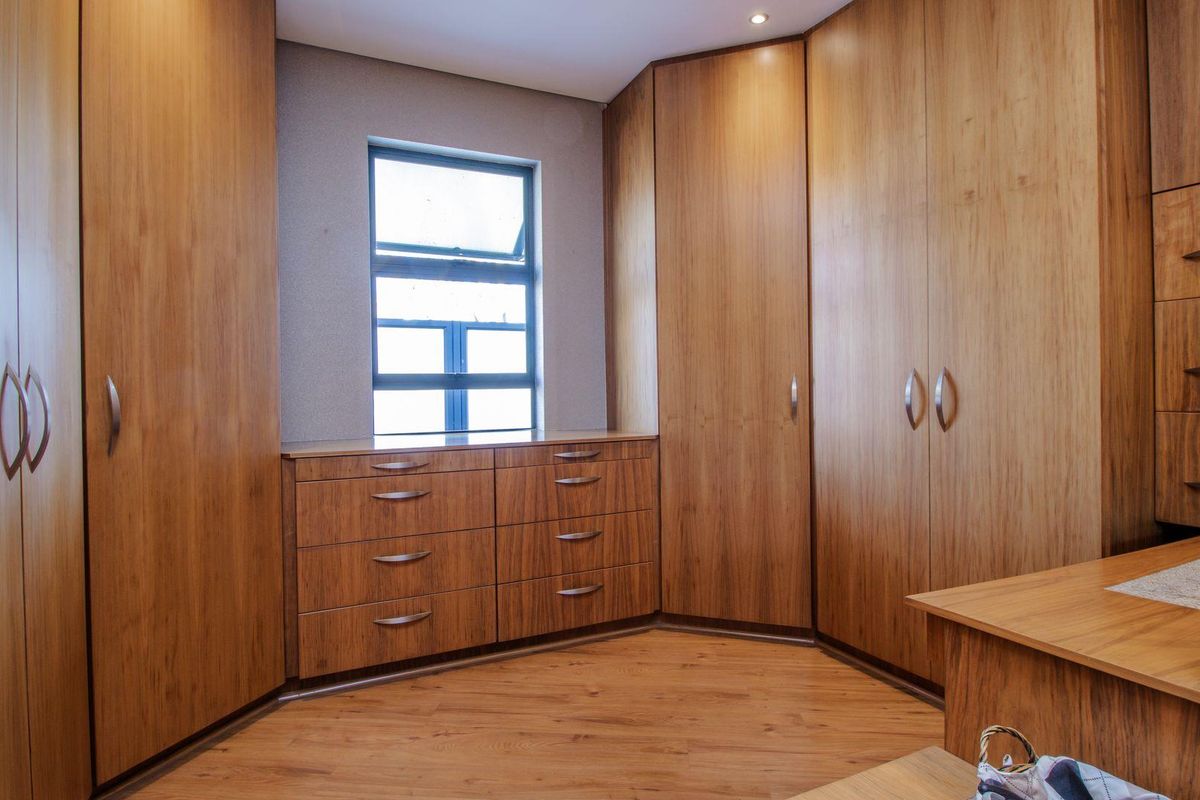 A bedroom featuring extensive built-in wooden cabinetry, integrated drawers, and wood-look flooring, providing ample storage space.