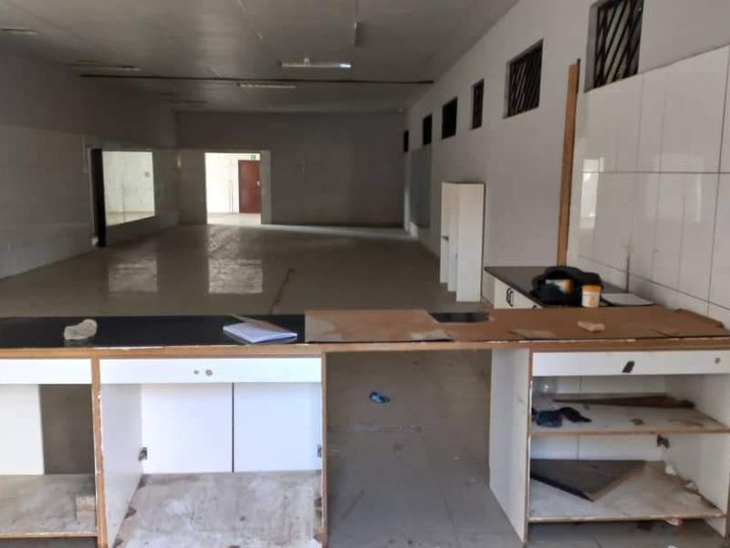 Spacious open-plan industrial unit featuring tiled walls, a large built-in service counter, and fluorescent lighting, suitable for various commercial or retail applications.