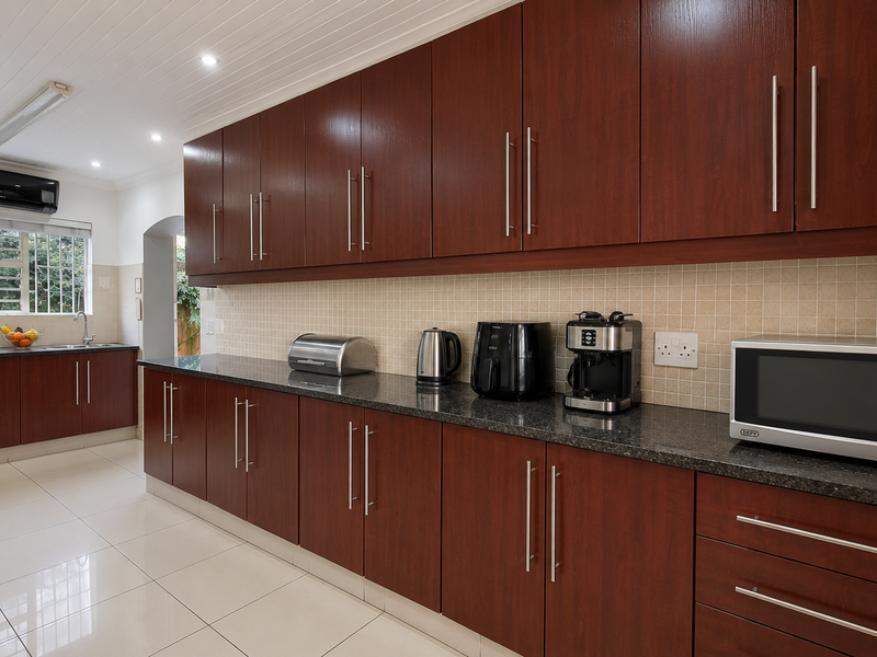 A well-maintained kitchen featuring extensive dark wood cabinetry, granite countertops, tiled backsplash, and modern recessed lighting.