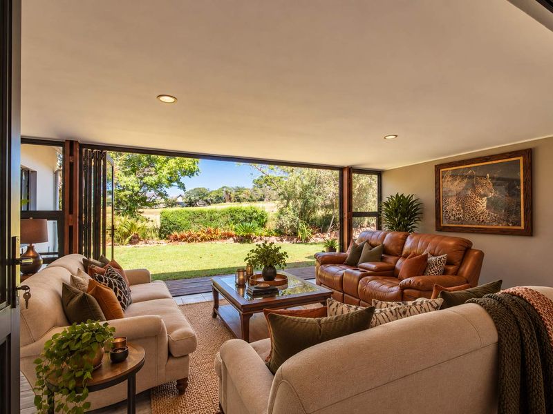 Spacious living room featuring large stacking glass doors that open onto a garden, providing seamless indoor-outdoor flow and abundant natural light.