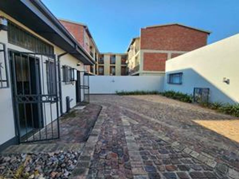 A paved rear courtyard area featuring a security gate and perimeter boundary walls within an apartment complex setting.