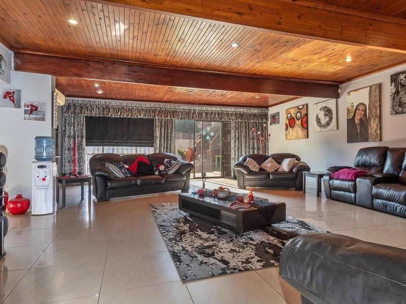 Spacious living room featuring a warm timber-clad ceiling with exposed beams, tiled flooring, and direct access to the outdoor area via sliding glass doors.