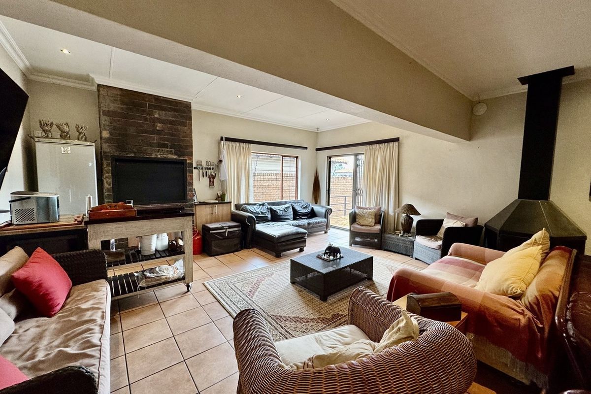 Spacious living area featuring tiled flooring, a built-in brick fireplace, a secondary metal fireplace, and direct access to the outdoor area via sliding doors.