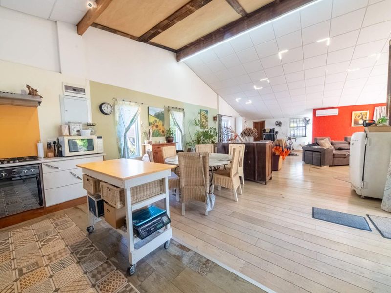 Spacious open-plan living area featuring exposed timber ceiling beams, a functional kitchen with built-in appliances, and a seamless transition between dining and lounge spaces.