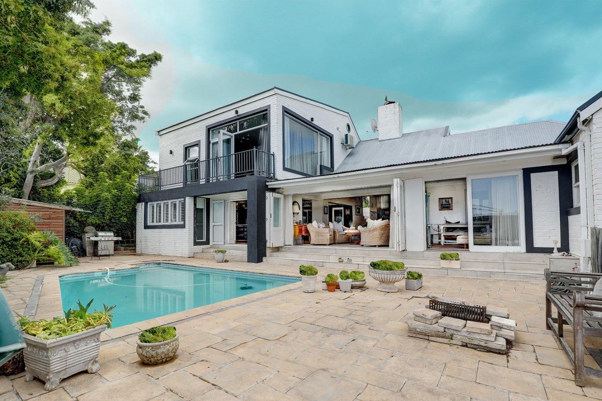 A spacious rear exterior featuring a swimming pool, paved patio area, and seamless indoor-outdoor flow through large folding doors.