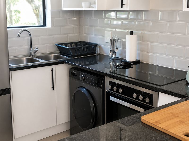 Modern kitchen featuring granite countertops, subway tile backsplash, built-in electric oven with glass cooktop, and integrated washing machine.