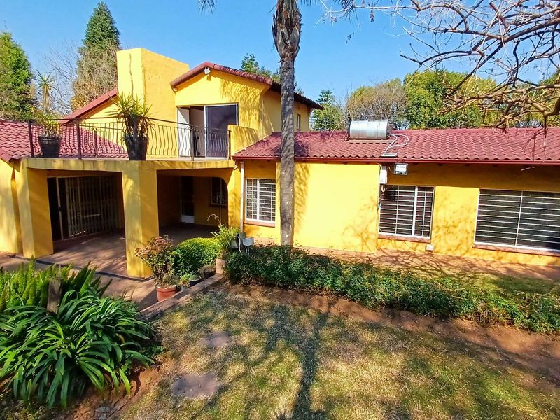 Rear view of a two-story house featuring a yellow stucco facade, tiled roof, solar water heater, and a covered patio area.