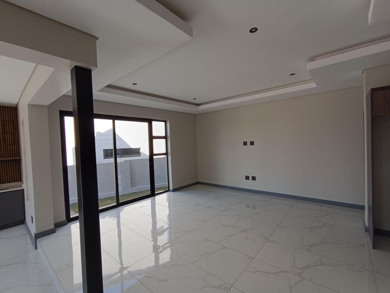 Spacious open-plan living area featuring modern recessed ceilings, downlights, large sliding glass doors, and high-gloss marble-look porcelain floor tiles.