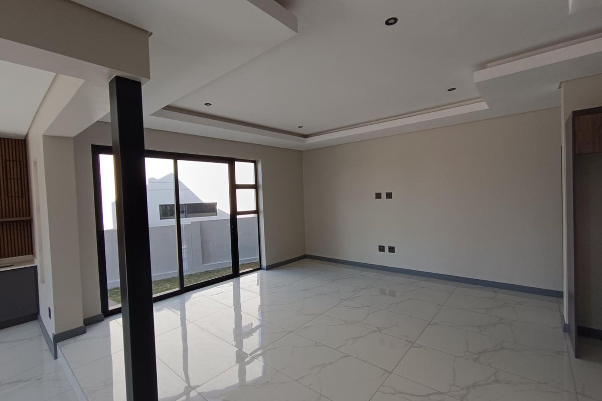 Spacious open-plan living area featuring modern recessed ceilings, downlights, large sliding glass doors, and high-gloss marble-look porcelain floor tiles.
