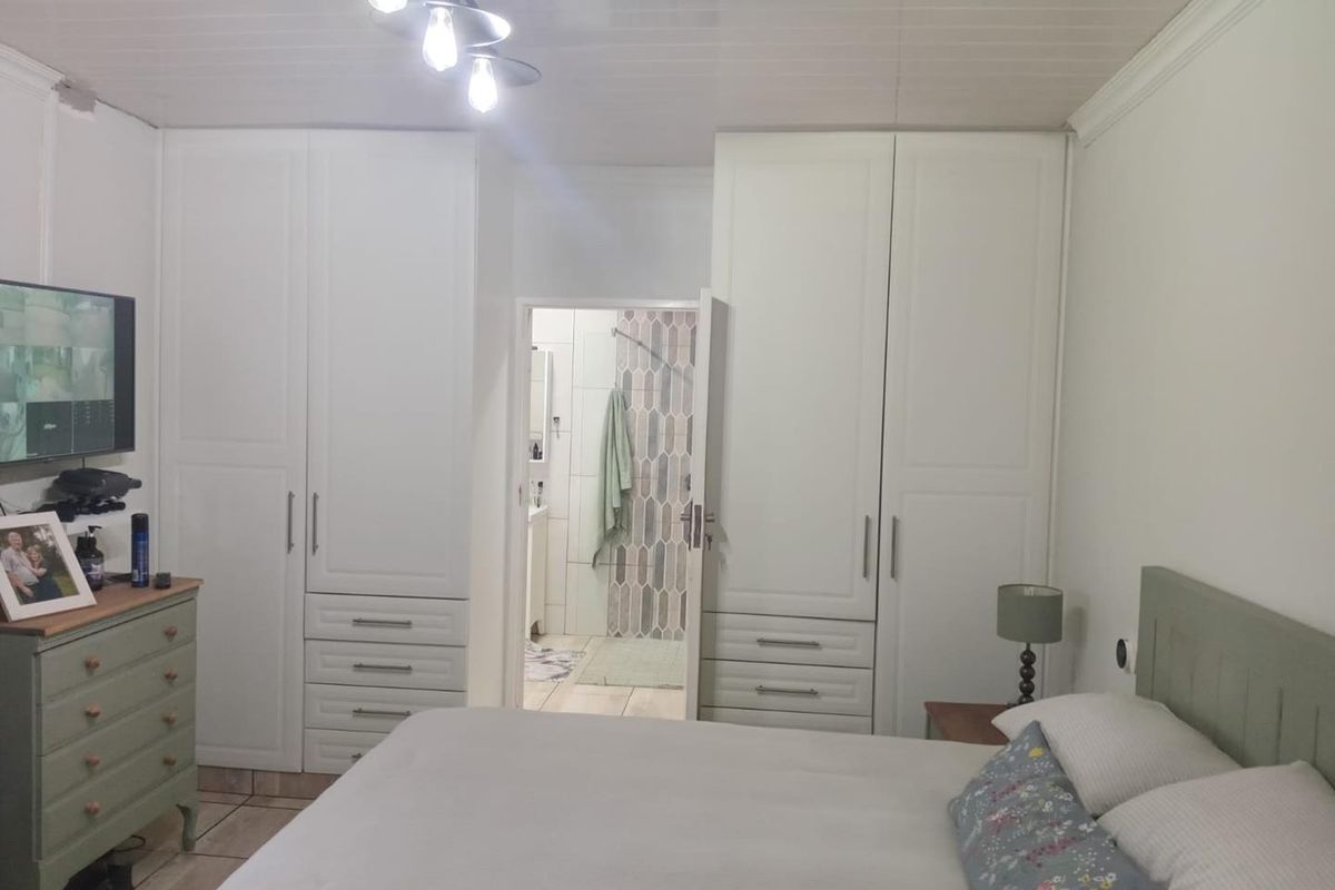 Bedroom featuring built-in wardrobes and an en-suite bathroom with tiled shower area.