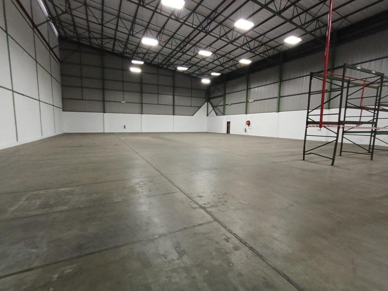 Spacious industrial warehouse unit featuring high ceilings, concrete flooring, and integrated fire safety systems, suitable for storage or manufacturing operations.